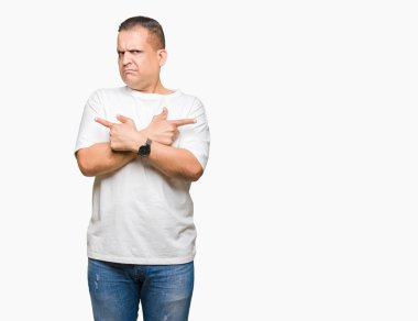 Orta yaş Arap adam wearig beyaz t-shirt üzerine izole arka plan için her iki parmak, farklı yönde ile katılmıyorum işaretleme