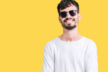 Yakışıklı delikanlı üzerinde güneş gözlüğü takıyor mutlu yüz ile gülümseyerek kameraya seyir silah geçti arka plan izole. Olumlu bir kişi.