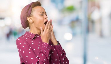 İzole arka plan üzerinde başörtüsü giyen güzel genç Afro-Amerikan kadın el ağzıyla kapsayan yorgun esneme sıkılmış. Restless ve uyku hali.