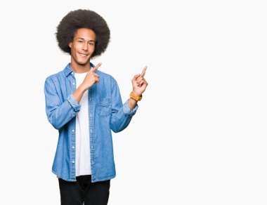 Gülümseyen ve iki elleri ve parmakları ile tarafına işaret kamera bakarak afro saçlı genç Afro-Amerikan adam.