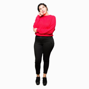 Kırmızı kazak ve çörek el ile çene düşünme hakkında soru, dalgın ifade üzerinde giyen genç güzel kadın. Düşünceli yüzüyle gülümsüyor. Şüphe kavramı.