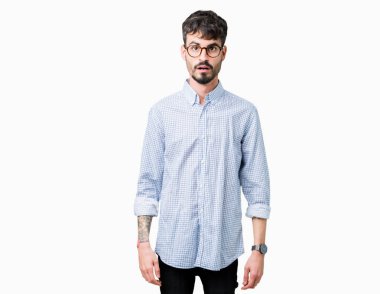 Korkuyor ve şok sürpriz ifade, korku ve heyecan yüz ile izole arka plan üzerinde gözlük takan genç yakışıklı adam.