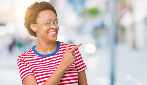 美丽的年轻非洲裔美国女人戴眼镜在孤立的背景欢快与微笑的脸指向用手和手指到一边 愉快和自然的表情在脸上 — 图库照片