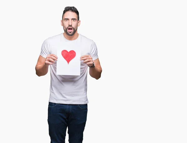 Joven Guapo Sosteniendo Tarjeta Con Corazón Rojo Sobre Fondo Aislado — Foto de Stock