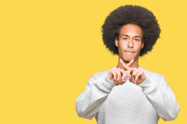 非洲青年美国男子与非洲头发穿着运动运动的运动运动衫拒绝表达交叉手指做负号 — 图库照片