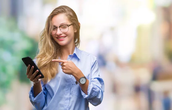 年轻美丽的金发女商人使用智能手机在孤立的背景非常高兴用手和手指指着 — 图库照片