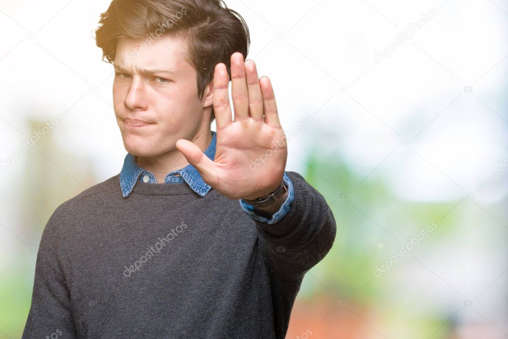 Young handsome elegant man over isolated background doing stop sing with palm of the hand. Warning expression with negative and serious gesture on the face.