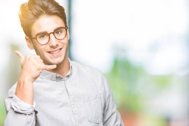 Yakışıklı delikanlı yapıyor gülümseyen izole arka plan üzerinde gözlük telefon hareketi ile el ve parmak telefonda konuşuyor gibi. Kavramları iletişim.