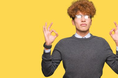 Afro saç gözlük giyen genç yakışıklı iş adamı rahatlayın ve gözleri ile gülümseyen meditasyon jest parmaklar ile kapalı. Yoga konsepti.