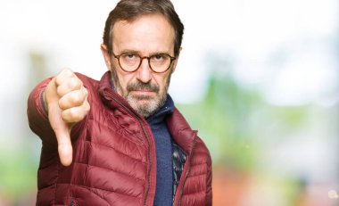 Gözlük ve mutsuz ve kızgın ret gösterilen ve başparmak aşağı hareketi ile negatif seyir kış ceket giyen orta yaş yakışıklı adam. Kötü ifade.