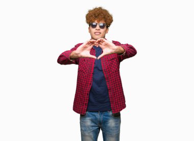 Yakışıklı genç afro saçlı aşık kalp simgesi ve elleriyle şekil gösteren gülümseyen güneş gözlüğü takıyor. Romantik kavramı.