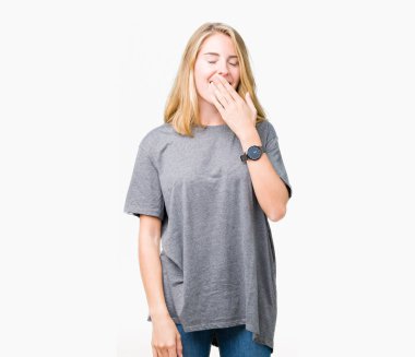 Büyük boy esneme rahat t-shirt izole arka plan üzerine sıkılmış giyen güzel genç kadın kapsayan ağız el ile yorgun. Restless ve uyku hali.