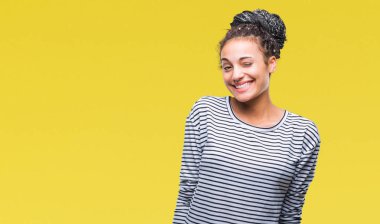 Genç seksi bir ifadeyle, neşeli ve mutlu yüzünü kameraya bakarak göz kırpıyor izole arka plan üzerinde kazak giyen saç Afro-Amerikan Kız örgülü.