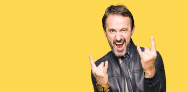 Orta yaş yakışıklı adam siyah deri ceket giyen deli ifade ile bağırarak elleri ile rock sembolü yapıyor. Müzik yıldızı. Ağır konsept.