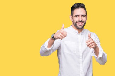 Genç iş adamı izole arka plan başarı işareti el ile pozitif jest yapıyor üzerinde başparmak gülümseyen ve mutlu. Neşeli bir ifadeyle, kazanan jest kameraya bakıyor.