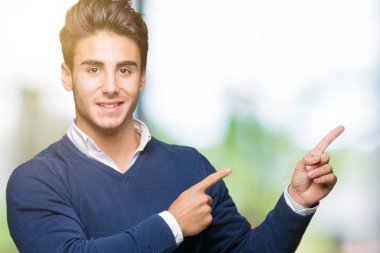 Genç yakışıklı iş adamı gülümseyen ve iki elleri ve parmakları ile tarafına işaret kamera bakarak izole arka plan üzerinde.