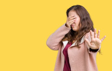 Artı boyutu genç kadın güzel kış ceket elleriyle gözlerini kapsayan izole arka plan üzerinde giyip dur jest ile acı ve korku ifadesi. Utandım ve negatif kavramı.