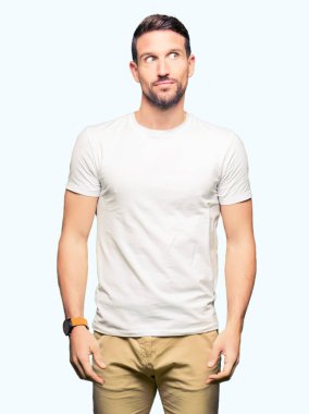 Yakışıklı adam görünümlü yan ve dik dik bakma uzağa düşünce gülümseyen casual beyaz t-shirt giyen.