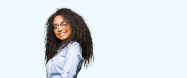 Kıvırcık saçlı Genç güzel iş kızı gözlük giyiyor açık el ile gülümseyen doğal girmek için davet