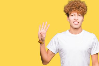 Gösterilen ve parmakları ile işaret casual beyaz t-shirt giyen afro saçlı Genç yakışıklı adam kendinden emin ve mutlu gülümseyerek süre dört numara.