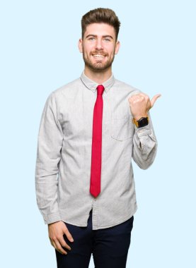 Seyir ve başparmak yanında yukarıyı mutlu yüz ile gülümseyen genç yakışıklı iş adamı.