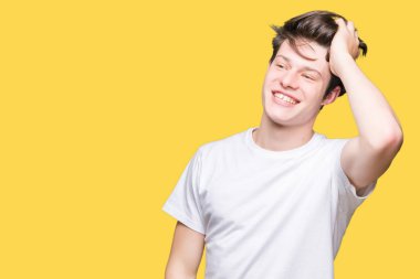 El hareketi ile kendine güvenen dokunaklı saç gülümseyerek, çekici poz izole arka plan üzerinde rahat beyaz t-shirt giyen genç yakışıklı adam