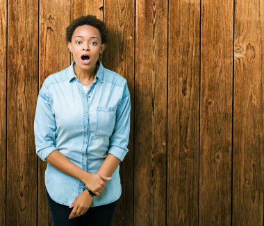 İzole arka plan üzerinde genç güzel Afrikalı Amerikan kadın korkuyor ve sürpriz ifade, korku ve heyecanlı yüz ile şok.