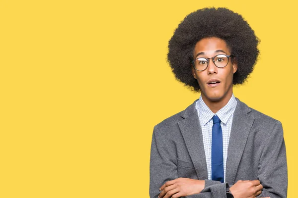 Young african american business man with afro hair wearing glasses afraid and shocked with surprise expression, fear and excited face.