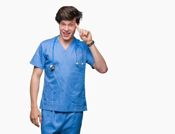 Médico Joven Vistiendo Uniforme Médico Sobre Fondo Aislado Sonriendo Señalando — Foto de Stock