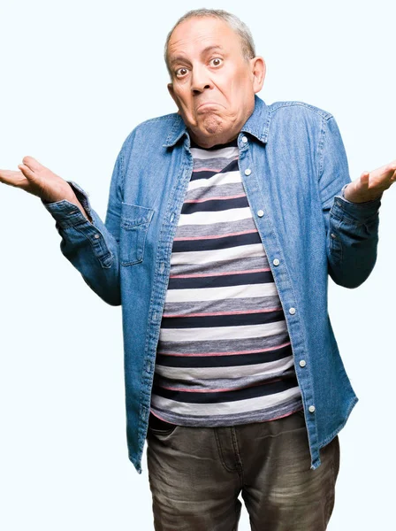 Przystojny Starszy Człowiek Ubrany Dżinsowa Kurtka Clueless Mylić Wyrażenie Ramiona — Zdjęcie stockowe