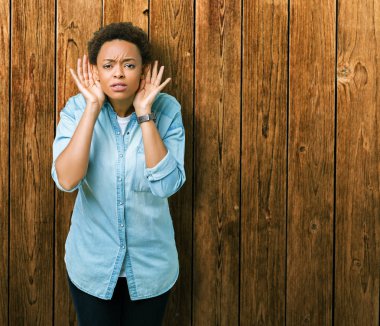 Her iki kulak jest, dedikodu için meraklı ellerde dinliyoruz izole arka plan üzerinde genç güzel Afrikalı-Amerikalı kadın. İşitme sorunu, sağır