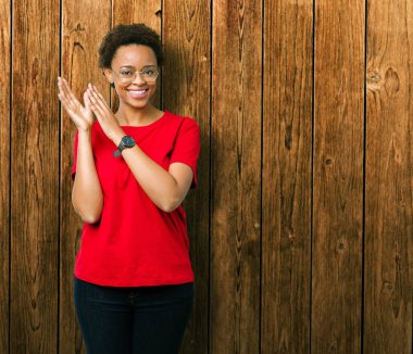 Güzel genç Afro-Amerikan kadın gözlük izole üzerinde arka plan Clapping ve mutlu ve neşeli, gururlu gülümseyen birlikte eller alkış