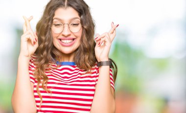 Giyen genç güzel kadın gülümseyen geçiş parmakları ile umut ve gözleri kapalı gözlükler. Şans ve batıl kavramı.