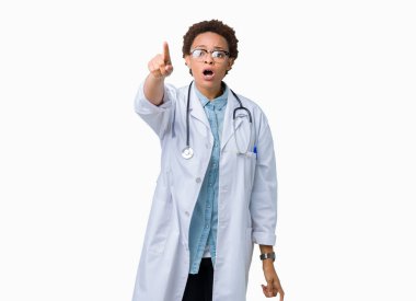 İzole arka plan ile sürpriz devam et, parmakla üzerinde tıbbi ceket giyen genç Afro-Amerikan doktor kadın ağzı açık ifade, önünde bir şey hayret