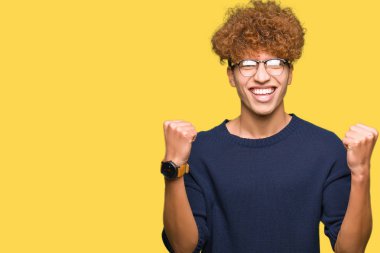 Afro kutluyor gözlük takan genç yakışıklı adamla şaşırttı ve başarı için kaldırdı kollarını açarak hayret ve gözleri açık. Kazanan kavramı.