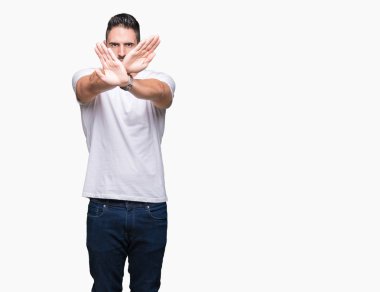 Beyaz izole arka planda beyaz t-shirt giyen yakışıklı adam ret ifadesi geçiş silah ve avuç içi negatif işareti, öfkeli yüz yapıyor