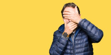 Orta yaş yakışıklı adam giyen kış kapsayan gözler kat ve ağız şaşırttı ve şok elleriyle. Duygu gizleme