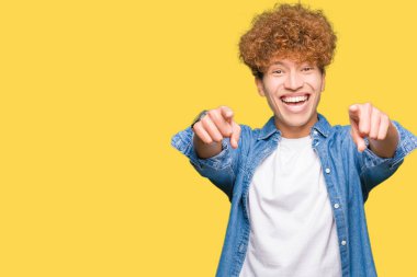 Afro saçlı kot giyen genç yakışıklı adam ceket size işaret ve parmaklar, kamerayla olumlu ve neşeli gülümseyen