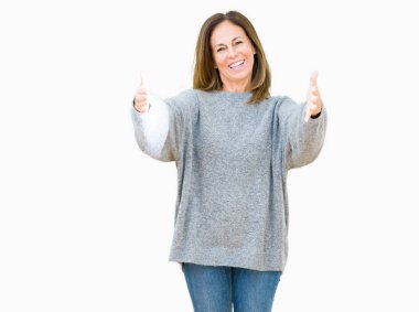 Sarılmak için kollarını açarak gülümseyerek kameraya bakarak izole arka plan üzerinde kış kazak giyen güzel orta yaş kadın. Neşeli ifade kucaklayan mutluluk.