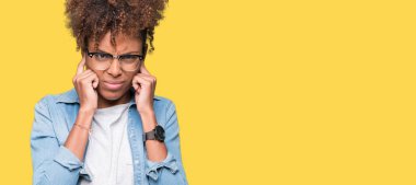 Yüksek sesle müzik gürültü rahatsız ifade parmaklarıyla kulaklarıyla kapsayan izole arka plan üzerinde gözlük güzel genç Afro-Amerikan kadın. Sağır kavramı.