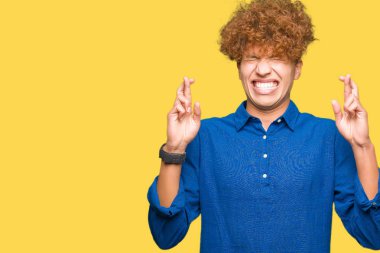 Umut ve gözleri kapalı geçiş parmaklarıyla gülümseyen afro saçlı Genç yakışıklı zarif adam. Şans ve batıl kavramı.