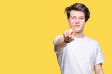 Casual beyaz t-shirt üzerinde izole giyen genç yakışıklı adam arka plan işaret parmağını ve kızgın ifade ile