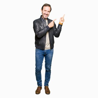Orta yaş yakışıklı adam gülümseyerek ve iki elleri ve parmakları ile tarafına işaret kamera bakarak siyah deri ceket.