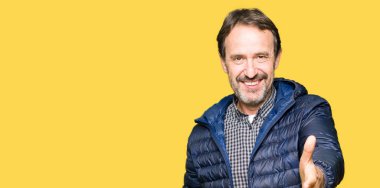 Orta yaş yakışıklı adam olarak tebrik ve konuksever dost sunan karşılıklı gülümseyen kış palto giyiyor. Başarılı iş.