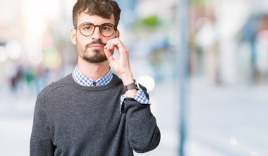 Genç yakışıklı akıllı adam izole arka plan ağız ve dudaklar üzerinde gözlük giyen parmakları ile zip olarak kapattı. Gizli ve sessiz, tabu konuşma