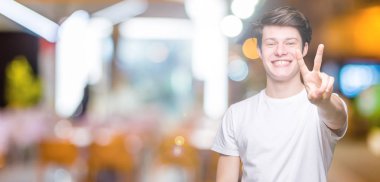 Yakışıklı delikanlı gösterilen ve parmakları ile işaret izole arka plan üzerinde rahat beyaz t-shirt giyen ikincisi ise kendinden emin ve mutlu gülümseyerek.