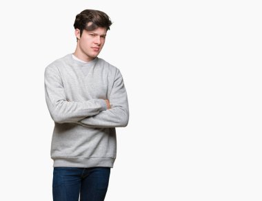 İzole arka plan üzerinde sweatshirt giyen genç yakışıklı sportif adam şüpheci ve sinir, kesişmiş kollar ile yüz üzerindeki ifade onaylamıyor. Negatif kişi.