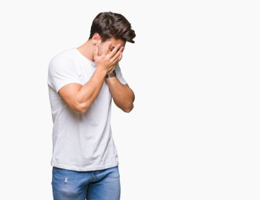 Yüzünü elleriyle ağlayarak süre kapsayan üzgün ifade ile izole arka plan üzerinde beyaz t-shirt giyen genç yakışıklı adam. Depresyon kavramı.