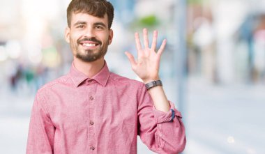 Yakışıklı delikanlı gösterilen ve parmakları ile işaret izole arka plan üzerinde pembe gömlek giymiş beş kendinden emin ve mutlu gülümseyerek iken numara.