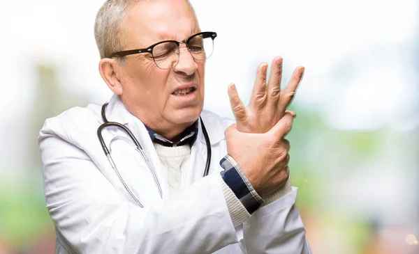 Handsome senior doctor man wearing medical coat Suffering pain on hands and fingers, arthritis inflammation